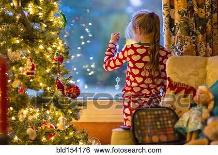 Caucasian girl looking out window near Christmas tree View Large Photo Image Stock Photograph - Caucasian girl looking out window near Christmas tree. Fotosearch