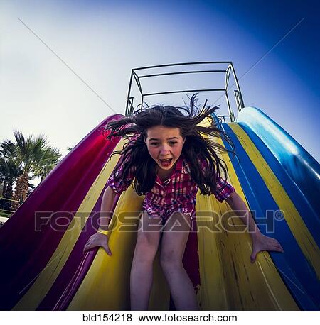 Stock Photo - Caucasian girl playing on slide. Fotosearch