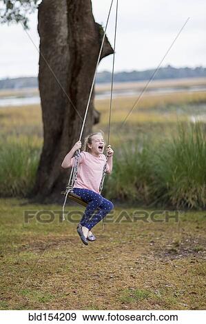 Caucasian girl playing on swing in field View Large Photo Image Stock Photo - Caucasian girl playing on swing in field. Fotosearch