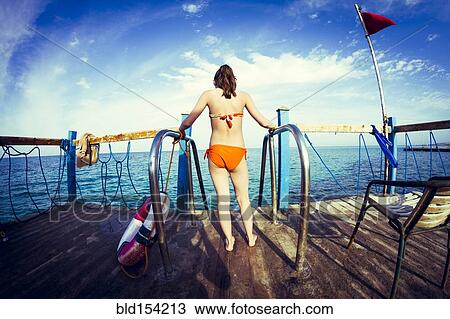 Caucasian girl standing at ladder over ocean View Large Photo Image Stock Image - Caucasian girl standing at ladder over ocean. Fotosearch