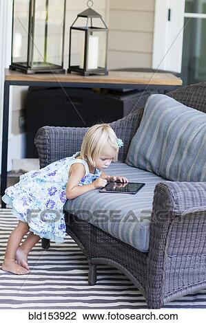 Stock Image - Caucasian girl using digital tablet on sofa. Fotosearch