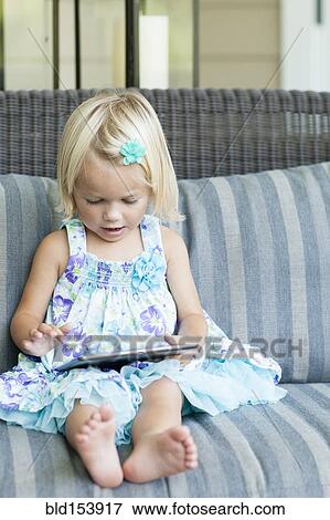Stock Photo - Caucasian girl using digital tablet on sofa. Fotosearch