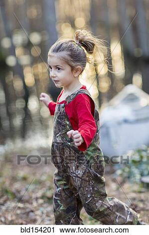 Stock Image - Caucasian girl wearing camouflage overalls outdoors. Fotosearch