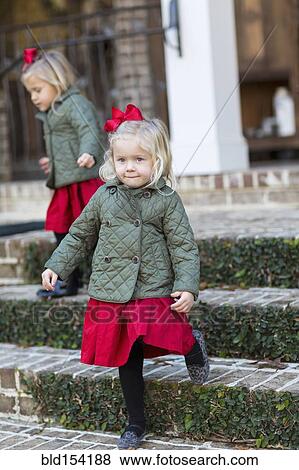 Stock Photo - Caucasian girls in holiday dresses on steps. Fotosearch