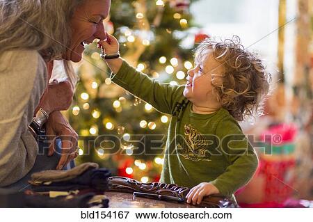 Stock Photo - Caucasian grandmother and grandson playing with toys near Christmas tree. Fotosearch