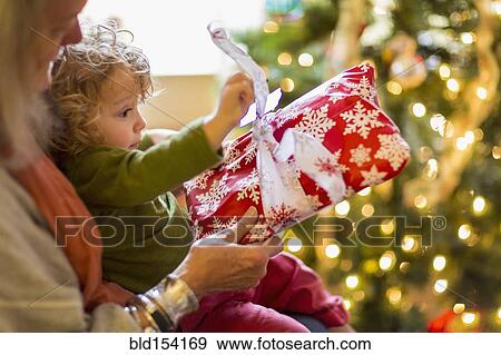 Caucasian grandmother and grandson opening presents near Christmas tree View Large Photo Image Stock Photo - Caucasian grandmother and grandson opening presents near Christmas tree. Fotosearch