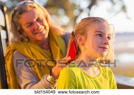 Stock Photo - Caucasian grandmother brushing hair of granddaughter. Fotosearch