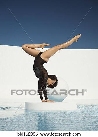 Stock Photography - Caucasian gymnast performing hand stand on ice floe. Fotosearch