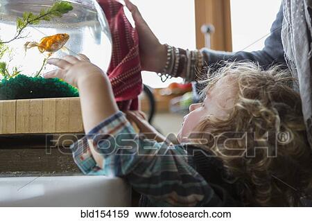 Stock Photo - Caucasian mother and baby boy examining fishbowl. Fotosearch