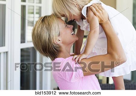 Stock Image - Caucasian mother and daughter playing on porch. Fotosearch