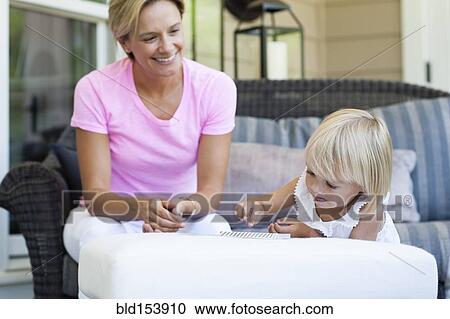 Stock Image - Caucasian mother and daughter sitting on porch. Fotosearch