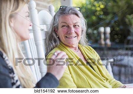 Stock Image - Caucasian mother and daughter talking on porch. Fotosearch