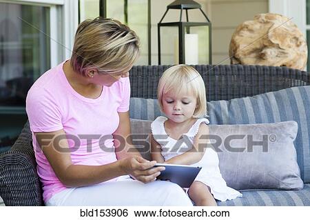 Caucasian mother and daughter using digital tablet on porch View Large Photo Image Stock Photograph - Caucasian mother and daughter using digital tablet on porch. Fotosearch