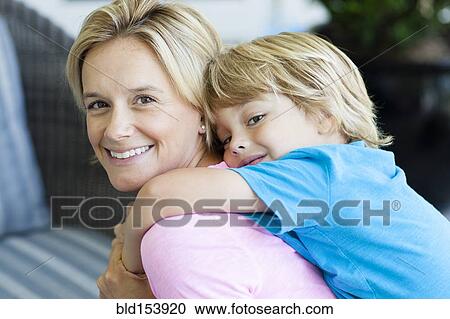 Stock Image - Caucasian mother carrying son piggyback. Fotosearch