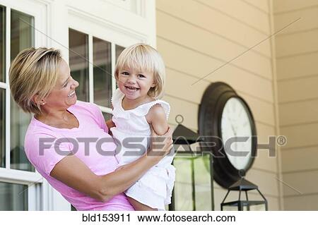 Stock Image - Caucasian mother holding daughter on porch. Fotosearch