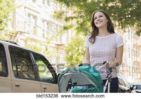Caucasian mother pushing stroller on urban sidewalk View Large Photo Image Stock Photograph - Caucasian mother pushing stroller on urban sidewalk. Fotosearch