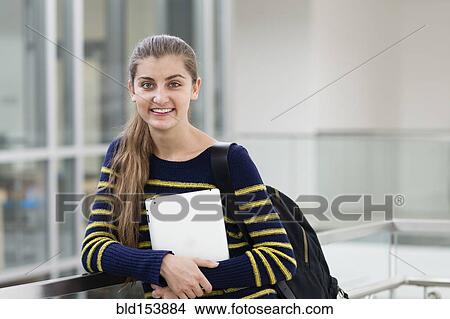 Picture - Caucasian student carrying digital tablet on campus. Fotosearch