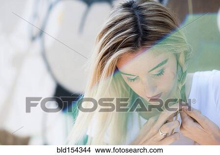 Picture - Caucasian woman braiding her hair. Fotosearch