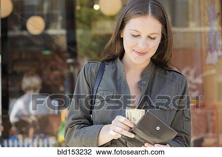 Stock Image - Caucasian woman counting money in wallet. Fotosearch