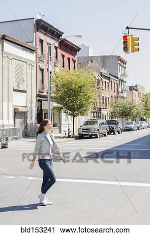 Stock Image - Caucasian woman crossing urban street. Fotosearch