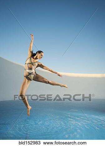 Stock Image - Caucasian woman dancing on swimming pool. Fotosearch