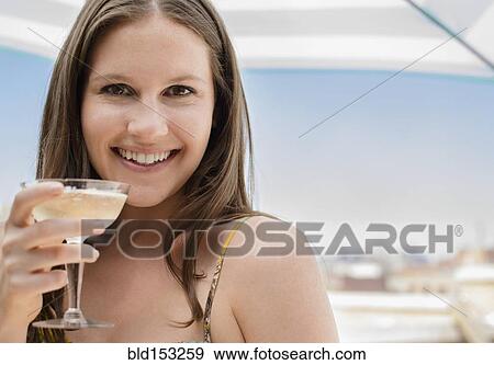 Stock Photo - Caucasian woman drinking cocktail outdoors. Fotosearch