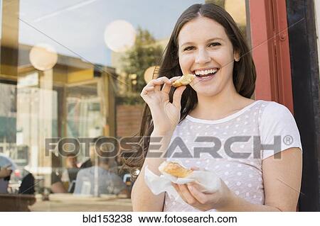Stock Photo - Caucasian woman eating outside cafe. Fotosearch