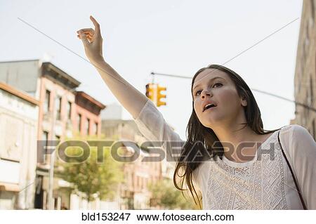 Stock Photo - Caucasian woman hailing taxi in city. Fotosearch