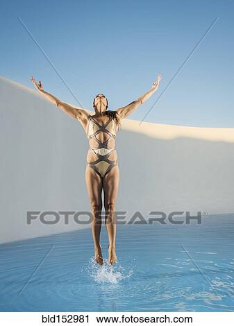 Stock Image - Caucasian woman jumping on swimming pool. Fotosearch