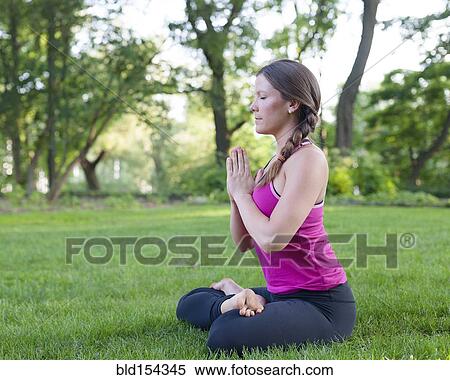 Stock Photography - Caucasian woman meditating in park. Fotosearch