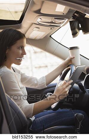Caucasian woman multi-tasking while driving car View Large Photo Image Stock Photography - Caucasian woman multi-tasking while driving car. Fotosearch