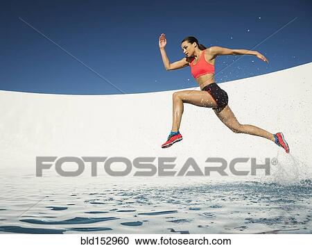 Stock Image - Caucasian woman running on water surface. Fotosearch