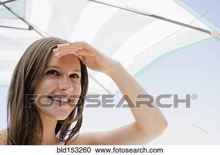 Caucasian woman shielding her eyes from sun View Large Photo Image Stock Image - Caucasian woman shielding her eyes from sun. Fotosearch