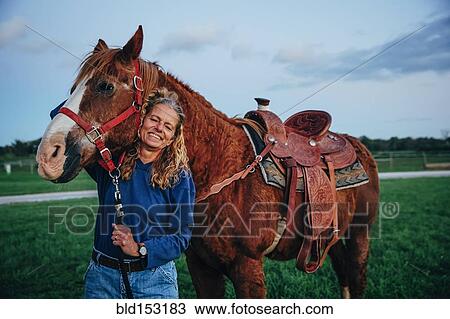 Stock Image - Caucasian woman smiling with horse on ranch. Fotosearch
