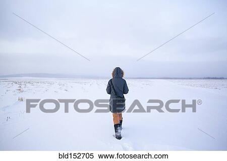 Stock Photography - Caucasian woman walking in snowy field. Fotosearch