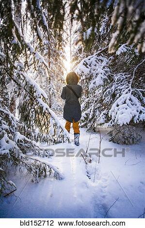 Stock Image - Caucasian woman walking in snowy forest. Fotosearch