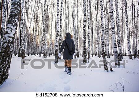Stock Photo - Caucasian woman walking in snowy forest. Fotosearch