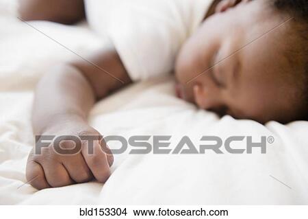 Picture - Close up of Black baby boy sleeping on bed. Fotosearch