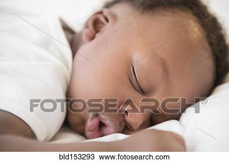 Stock Image - Close up of Black baby boy sleeping on bed. Fotosearch