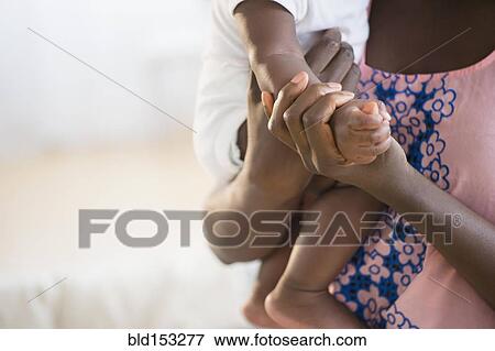 Stock Photo - Close up of Black mother holding arm of baby. Fotosearch