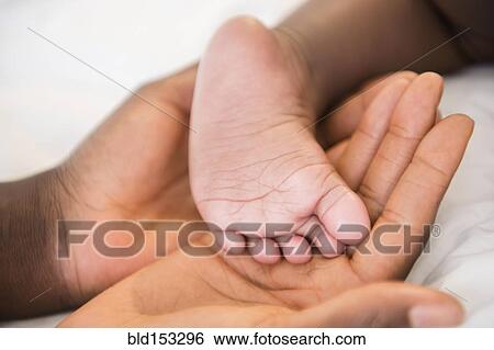 Close up of Black mother holding foot of baby View Large Photo Image Stock Photograph - Close up of Black mother holding foot of baby. Fotosearch