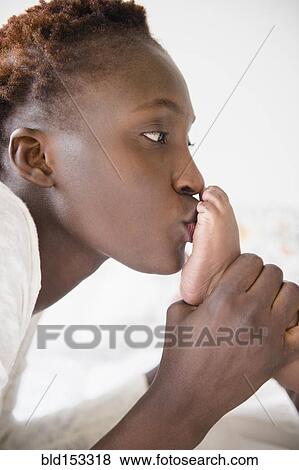 Stock Photo - Close up of Black mother kissing feet of baby boy. Fotosearch