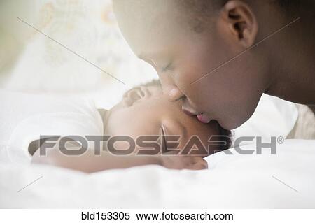 Stock Photography - Close up of Black mother kissing forehead of baby boy. Fotosearch
