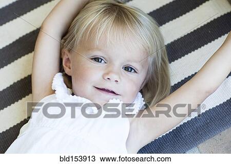 Stock Image - Close up of Caucasian girl laying on striped rug. Fotosearch