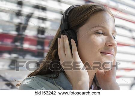 Stock Image - Close up of Caucasian woman listening to headphones. Fotosearch