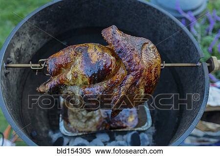 Stock Photography - Close up of chicken cooking on rotisserie barbecue. Fotosearch