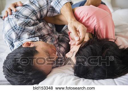 Close up of couple cuddling on bed View Large Photo Image Stock Photo - Close up of couple cuddling on bed. Fotosearch