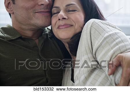 Stock Image - Close up of couple hugging on sofa. Fotosearch