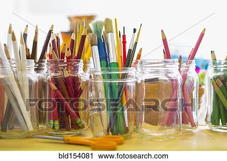 Stock Image - Close up of jars of colored pencils and paintbrushes. Fotosearch