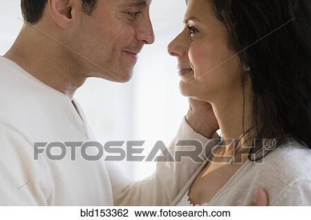 Stock Image - Close up of man holding face of wife. Fotosearch